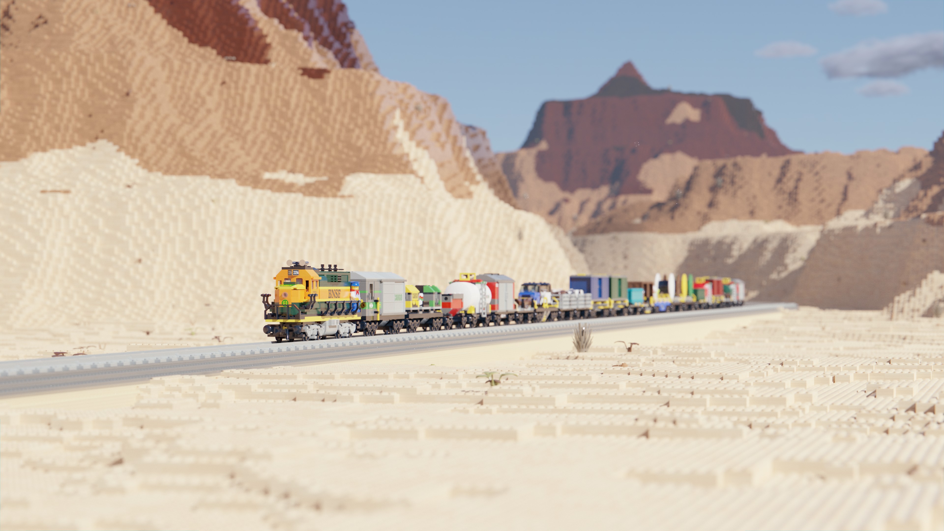 Image of a Lego train travelling through a desert landscape on a sunny day with some clouds in the sky.